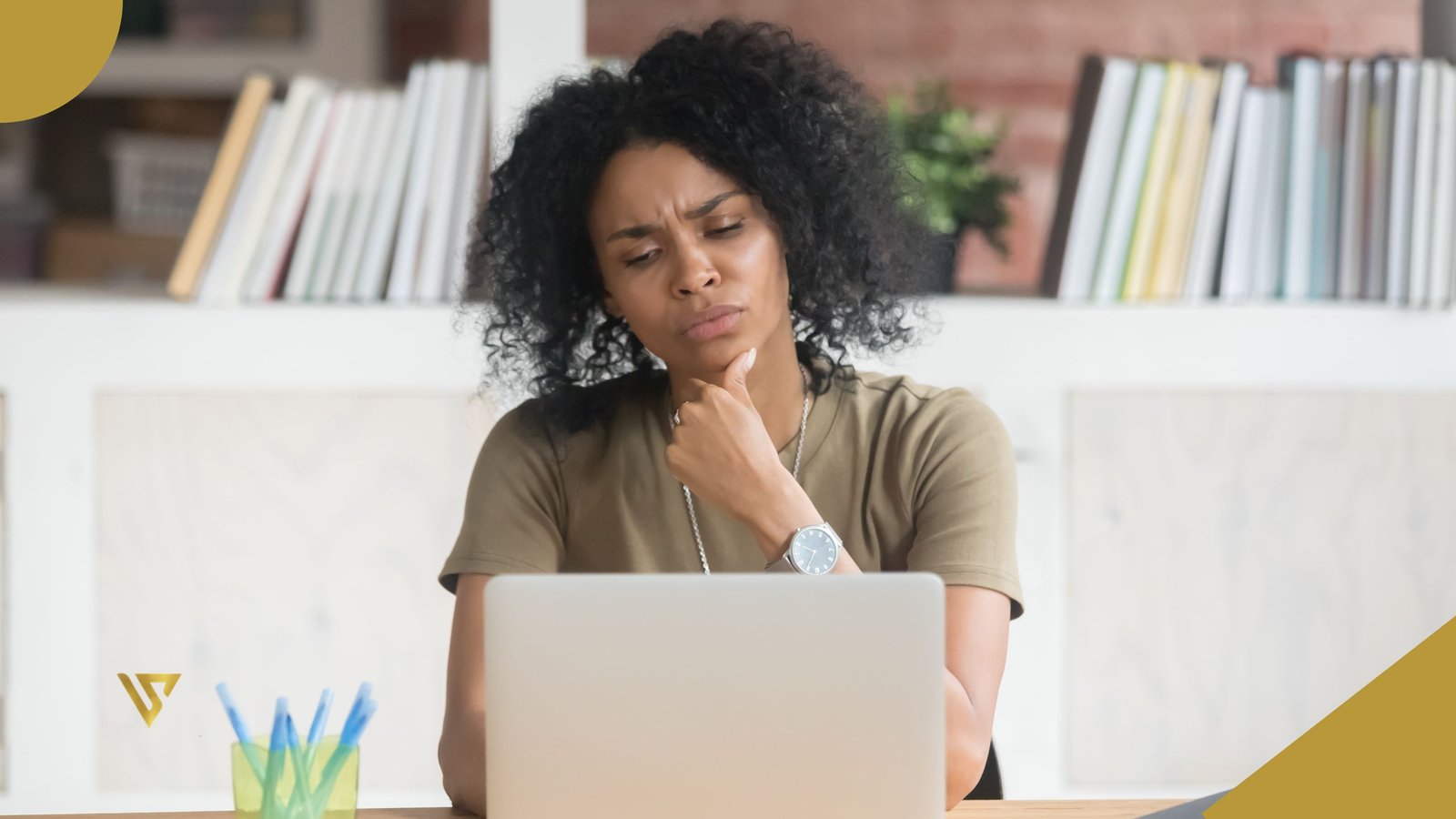 An adult woman who is sitting, with curly black hair, wearing an olive-green shirt, a silver necklace, and a watch on her left wrist. Her left hand is resting on her chin. A wooden desk with a silver laptop on top, and a yellow pencil holder containing blue pens, beauty spa by val, is Hydrafacial or Microdermabrasion Better for Your Skin Type