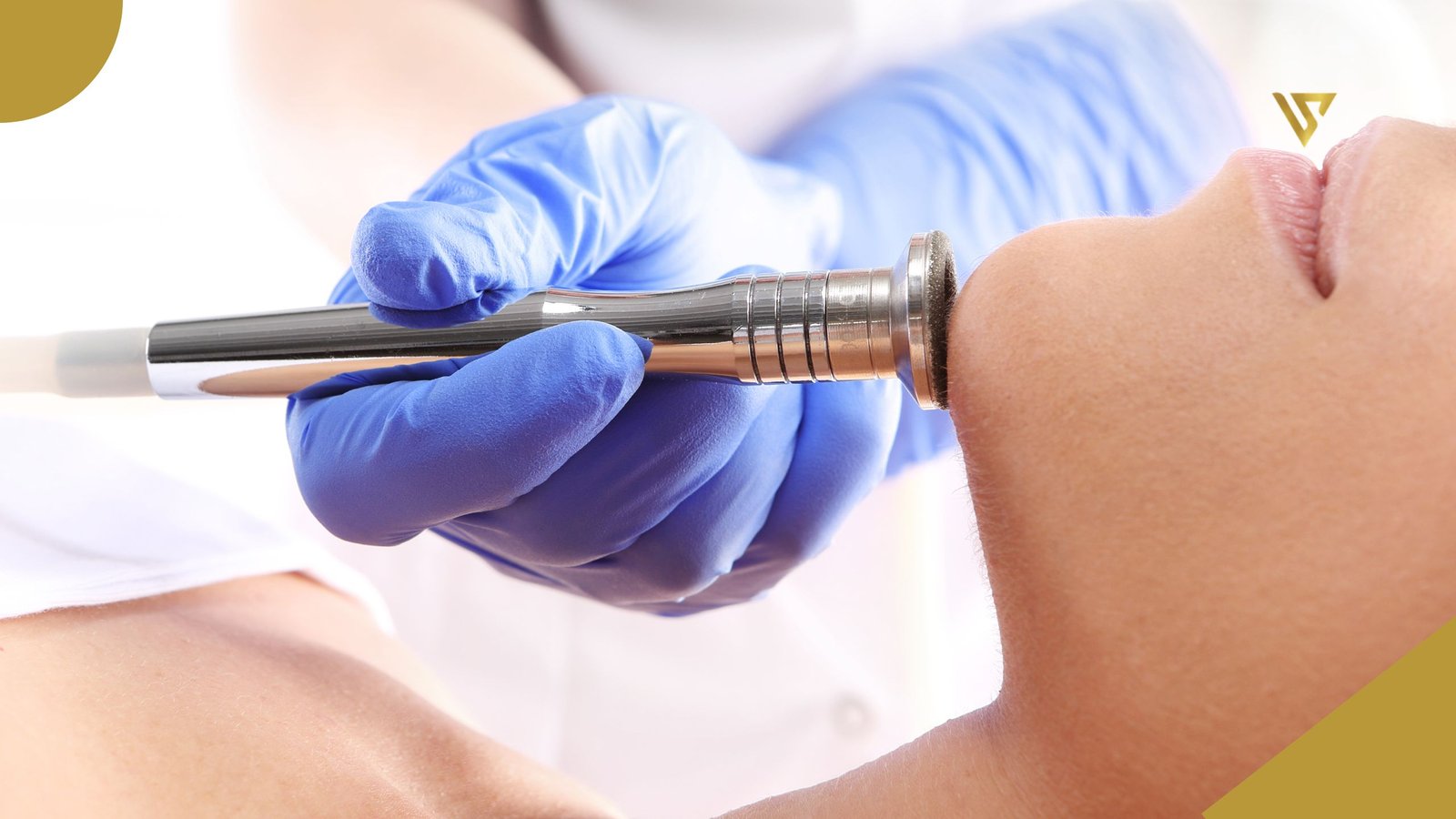 Right hand wearing a neoprene glove, a skin instrument resting on the chin of a woman who is lying down with a sheet covering her chest, beauty spa by val, hydrafacial vs microdermabrasion, which treatment Is better for your skin.