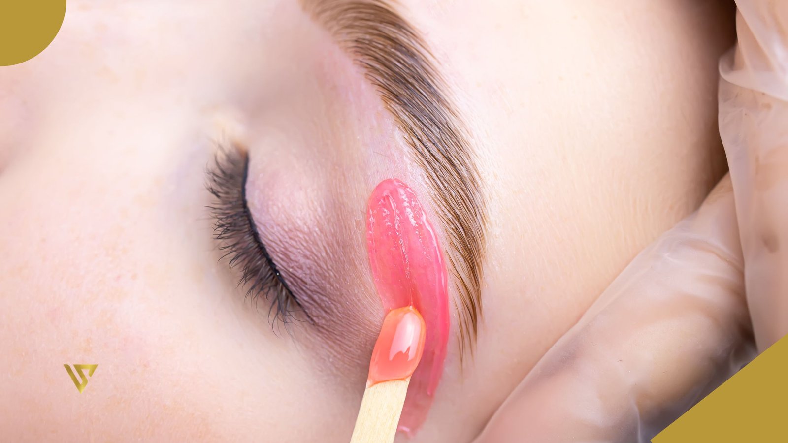 Close-up of a woman’s closed eye during eyebrow waxing treatment, with pink wax applied around the eyebrow. Brow Lamination vs. Eyebrow Wax: Which One Is Right for You? Beauty Spa by Val